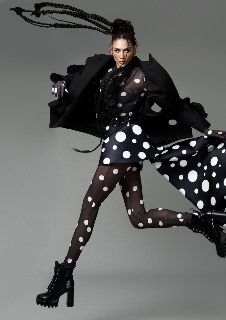 Á hậu Võ Hoàng Yến diện trang phục với chi tiết chấm bi trắng làm điểm nhấn trên nền đen. Nhà thiết kế kết hợp bodysuit, chân váy bất đối xứng cùng áo khoác bên ngoài.