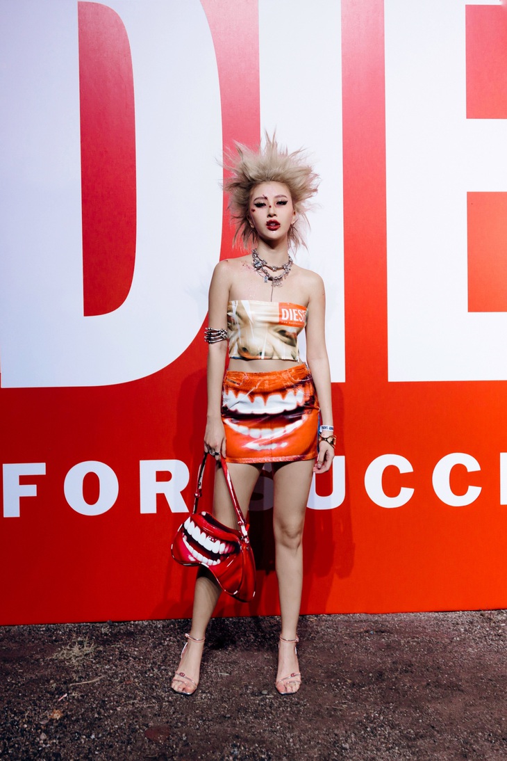 Thiết kế Quỳnh Anh Shyn diện trong show Diesel đều thuộc bộ sưu tập Thu Đông 2023 của thương hiệu này. Đó là chiếc áo quây với họa tiết một khuôn mặt được phóng to đến mức “siêu thực”, cộng thêm hiệu ứng nếp nhăn độc đáo và phủ một lớp sáng nhẹ cùng chân váy phối denim lấy cảm hứng từ quần jean 5 túi.